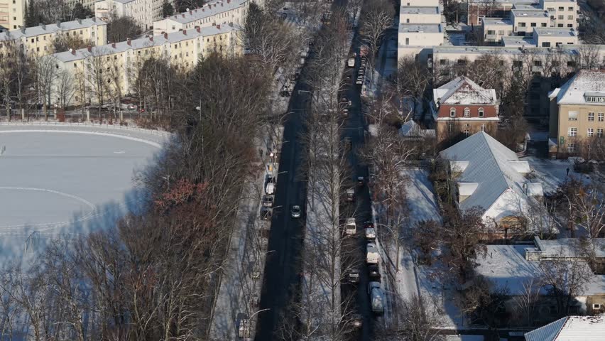 Cars driving along a road in Berlin next to a frozen lake during a sunny winter day