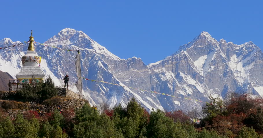Namche Bazaar, Nepal, push-in shot of a white Buddhist stupa with prayer flags revealing Mount Everest and Mount Lhotse peaks in the background.