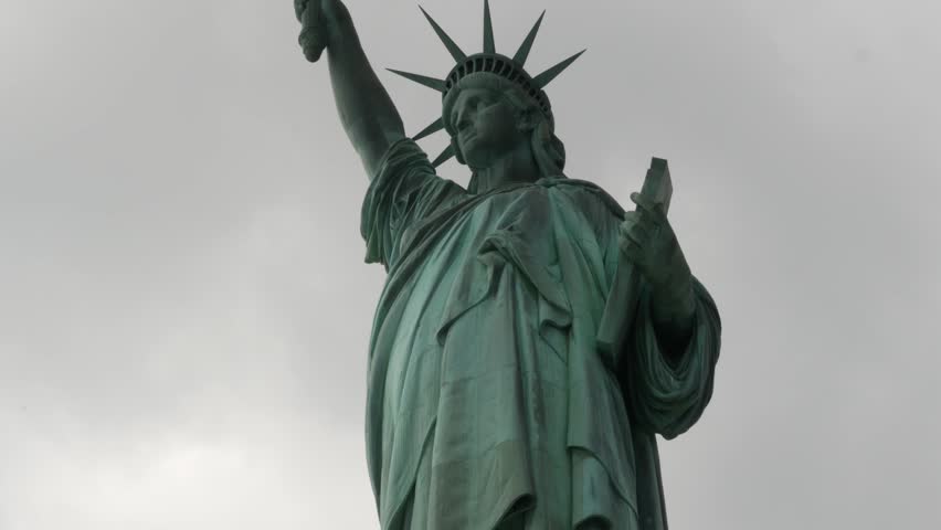 Statue of Liberty on Liberty Island, New York, United States. Blue cooper monument, symbol of democracy and patriotism near Manhattan, NYC USA. Clouds on sky. American independence. Torch and crown.