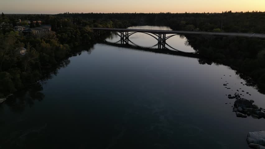 Aerial drone view of the Sacramento River and bridge in Sacramento, California. Scenic urban landscape featuring flowing water, bridge architecture, and surrounding city environment. Cinematic bird’s-eye perspective ideal for travel, transportation, tourism, and city infrastructure concepts.
