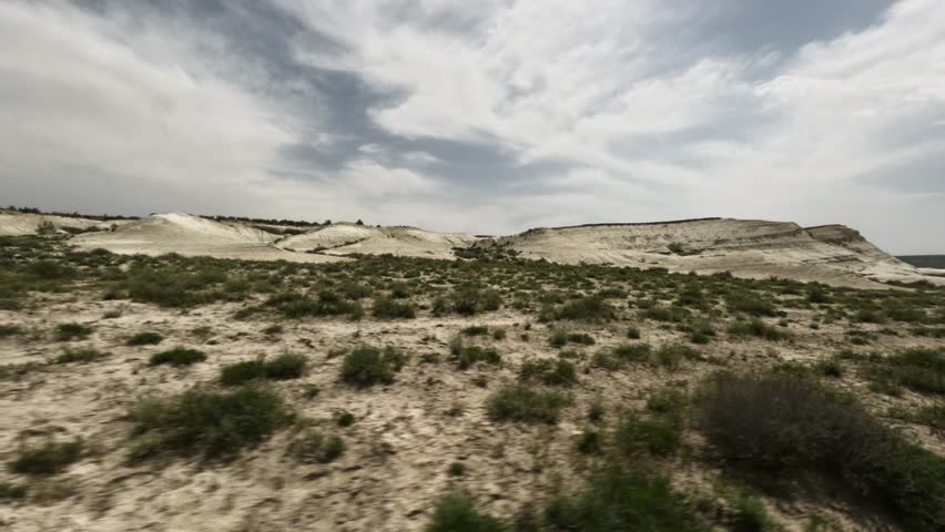 SUV perspective captures a desert landscape with rolling hills and sparse vegetation, showcasing the natural beauty of the arid environment