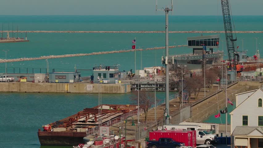 Lake Michigan harbor in Chicago with a loaded barge, construction crane, breakwater and worksite activity under clear cold-season light.