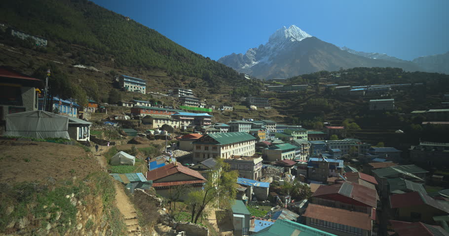 Namche Bazaar, Nepal, aerial orbit drone shot of the Sherpa village featuring colorful rooftops against the backdrop of the rugged Kongde Ri mountain peak