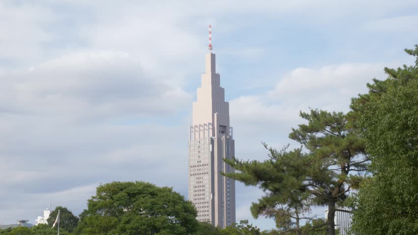 NTT Docomo Yoyogi Skyscraper Seen From Meiji Jingu Shrine Garden With Black Pine Trees In Tokyo, Japan. - wide shot