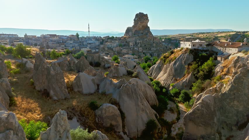 Aerial view of Ortahisar Castle in Cappadocia, Turkey. Cave houses, fairy chimneys and green valley scenery surround the rocky fortress.
