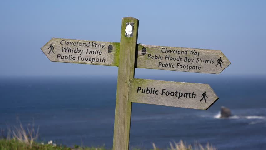 Wooden signpost showing directions to Whitby and Robin Hoods Bay along Cleveland Way in North York Moors National Park, UK