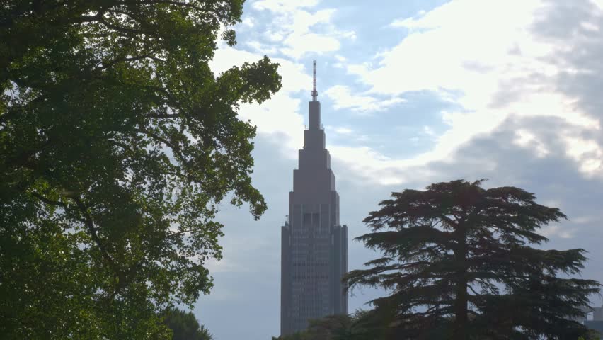 NTT Docomo Yoyogi Building Towering Over The Greenery Of Shinjuku Gyoen National Garden In Tokyo, Japan. - wide shot