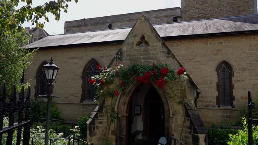 Climbing red roses frame the entrance to Little Saint Mary s Church in Cambridge, UK, adding a touch of vibrant color to the historic stone facade
