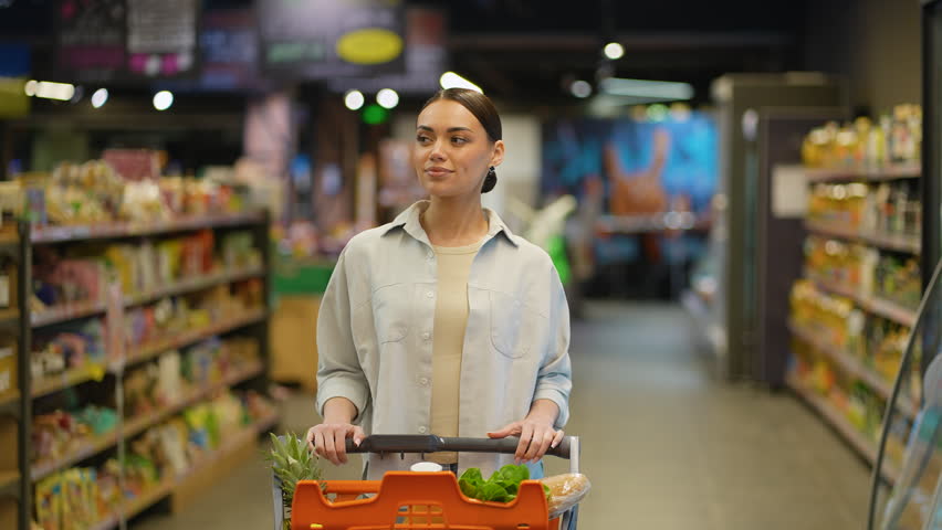 Woman pushing shopping cart in supermarket aisle