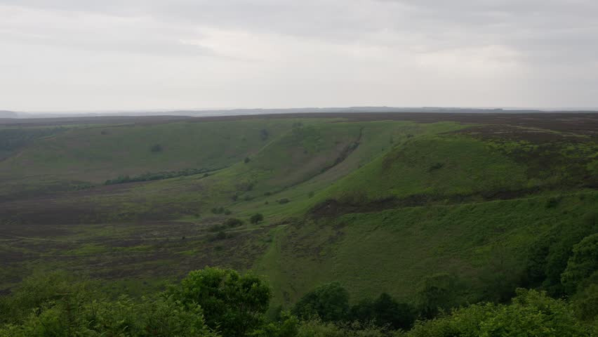 Green hills surrounding a valley under a cloudy sky in North York Moors National Park, United Kingdom