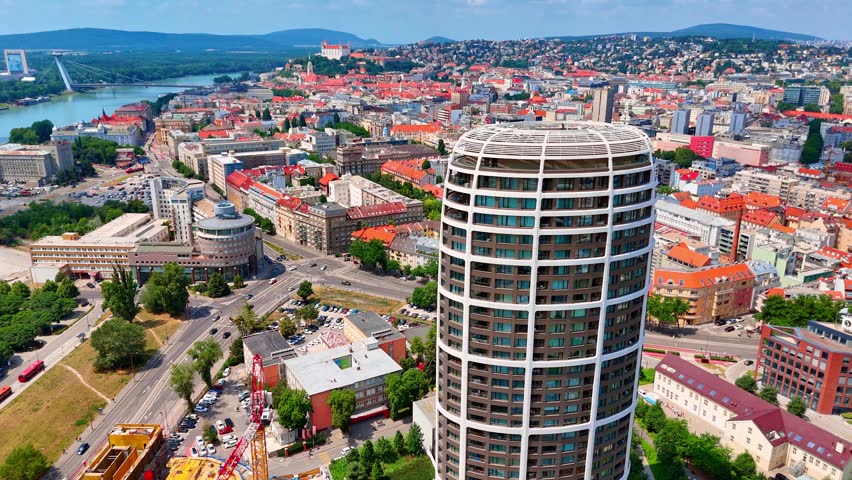 Cityscape with Bratislava Castle on hill, Bratislava, Slovakia. Drone perspective revealing the old town red roofs and a modern residential skyscraper in foreground.