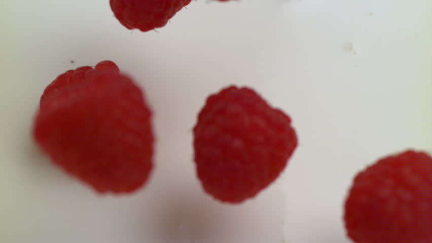 Red raspberries falling into cream and splashing in slow motion.