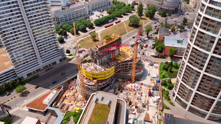 Sunlight over an urban construction site, Bratislava, Slovakia. Elevated view focusing on cranes, yellow formwork structures and building development in the city.