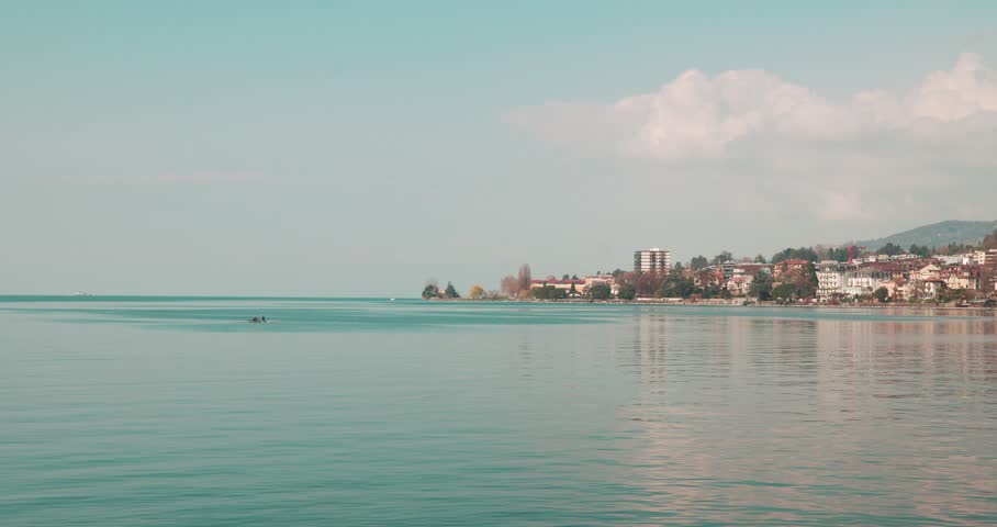 Calm Waters of Lake Geneva with Montreux Waterfront in Switzerland - Peaceful view across Lake Geneva towards the waterfront of Montreux, Switzerland. Calm lake conditions and distant alpine scenery create a tranquil European travel landscape.