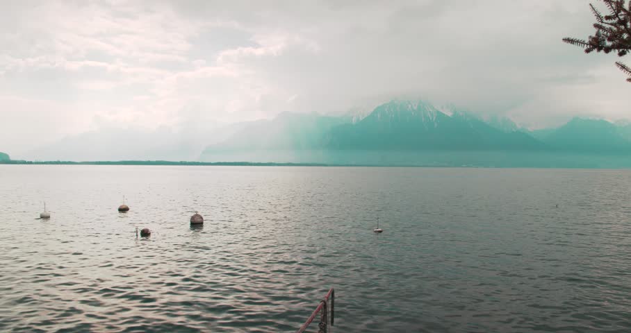 Misty Mountain Landscape Across Lake Geneva Near Montreux - Atmospheric view across Lake Geneva with distant mountains partially hidden by mist and low cloud. Tranquil Swiss landscape captured along the shoreline near Montreux.