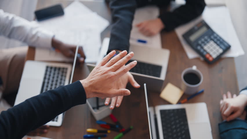 Multiethnic businesspeople folding hands, closeup view in office, teamwork. Corporate culture and business, partnership and successful deal, unity and collaboration for success in business, together