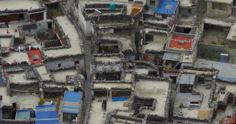 Kagbeni Mustang Nepal, static aerial hovering shot directly above traditional stone brick houses and narrow alleys in the historic mountain village.