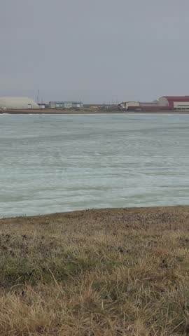 Arctic tundra in Utqiagvik, Alaska showing a frozen lagoon in background.