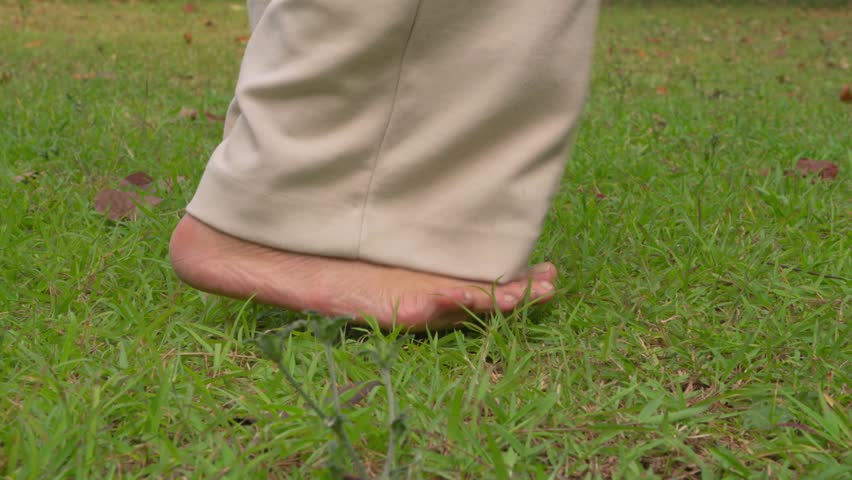 barefoot person walking slowly across fresh green grass in a park or garden