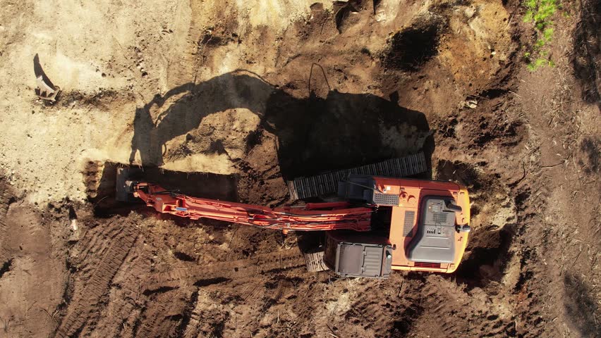 Aerial view from above of an excavator operating at dawn.