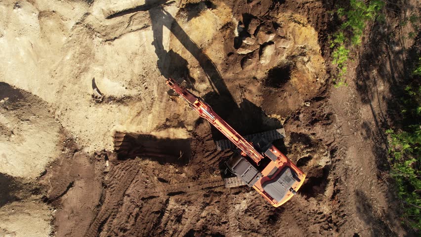 Aerial view from above of an excavator operating at dawn.
