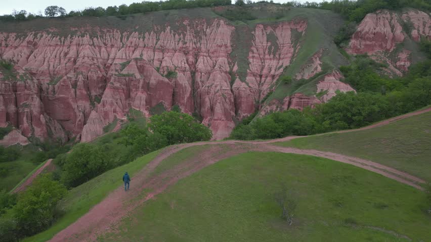 Hiker exploring the stunning red ravine of Rapa Rosie in Transylvania, Romania. Geological reservation with badlands