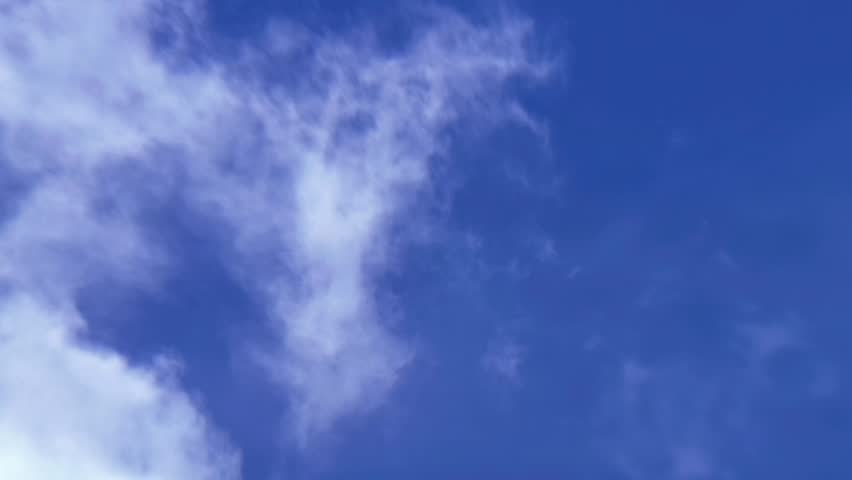 Birds Flying Across Bright Blue Sky with Passing Clouds