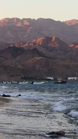 Vertical shot of Picturesque waterfront with vessels. Sea waves on sandy beach