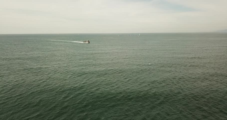 Aerial view of a small boat moving across the calm waters of the Pacific Ocean near the coast of Long Beach, California, United States.