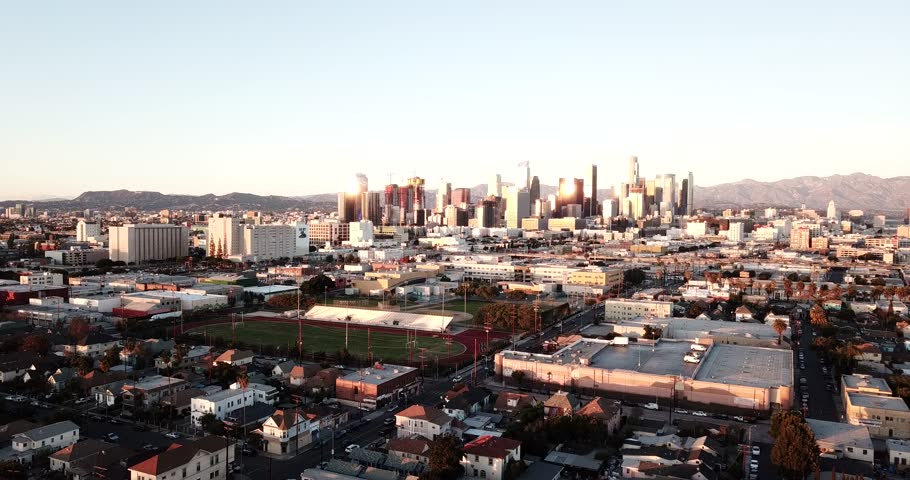 Aerial view of the Los Angeles skyline during golden hour with urban sprawl and distant mountains in Los Angeles, California, United States.