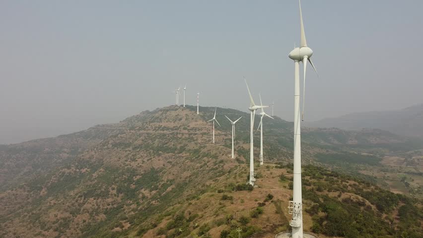 Aerial shot of many wind turbines on a misty mountain ridge generating green energy in the morning.