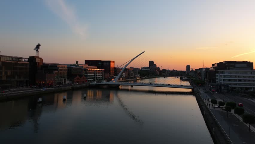 The Samuel Beckett Bridge stands over the River Liffey during a golden sunset in Dublin. Ideal for travel content or urban documentaries.