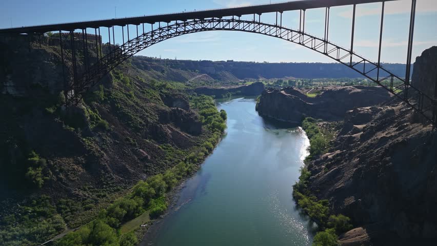 Aerial push in shot of Perrine Memorial Bridge over Snake River in Twin Falls, Idaho with BASE jumpers leaping from the top.