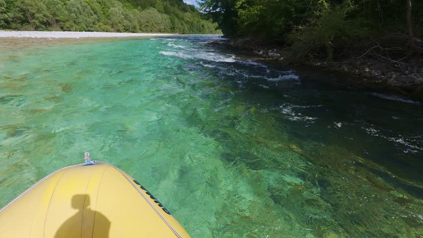 POV of an exciting whitewater rafting adventure on the emerald waves of the Soca River in Slovenia. First-person view of an inflatable boat navigating rapid stream currents in a canyon forest