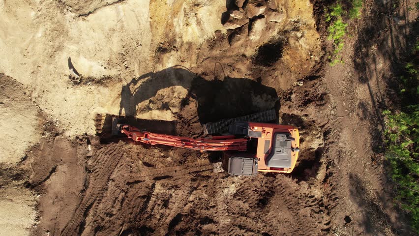 Aerial view from above of an excavator operating at dawn.