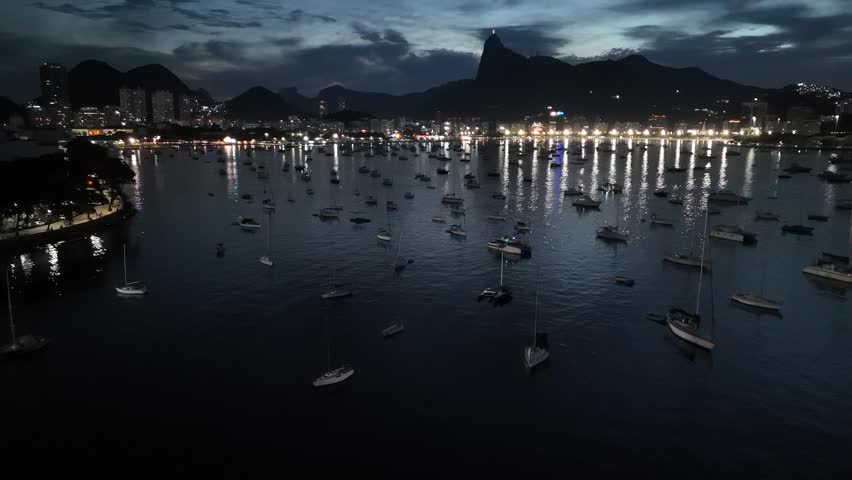 Aerial view of Botafogo Bay at night with numerous sailboats anchored in the calm water and city lights reflecting on the surface, Rio de Janeiro, State of Rio de Janeiro, Brazil.