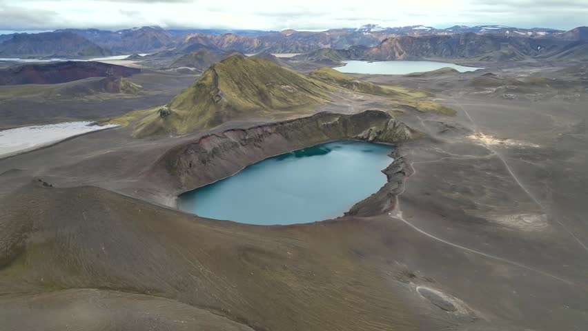 Aerial view of the Hnausapollur crater lake with its vibrant blue water surrounded by volcanic slopes and rugged terrain in Hella, Rangarthing ytra, Iceland.