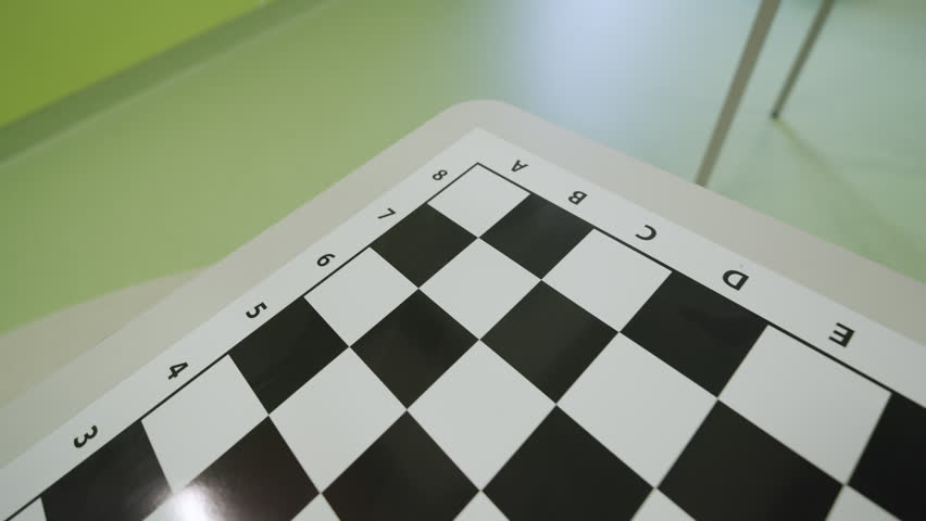 Contrasting chessboard printed directly onto white table surface. Board features algebraic notation with letters and numbers along edges
