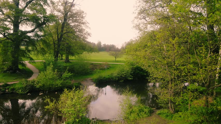 View of lake surrounded by lush trees in Spring wide aerial drone 4k shot selective focus