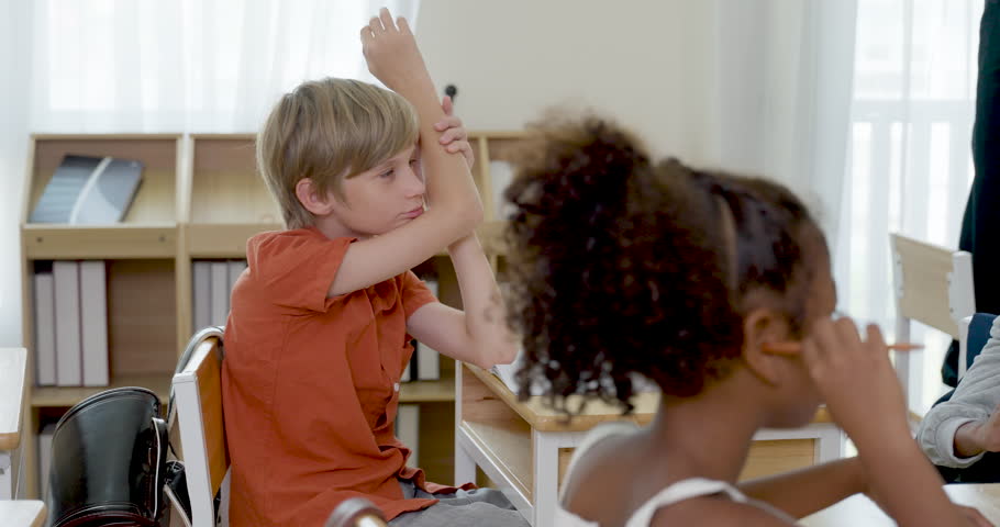 Male elementary teacher continues writing alphabet words on chalkboard, preparing basic classroom lesson notes for back to school first day, primary education routine, and student attention skills.