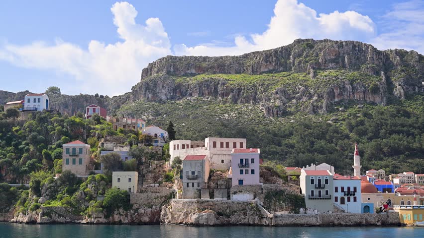 Picturesque seaside village of Kastellorizo on a Greek island with its colorful houses, clear blue sea and mountains in the background