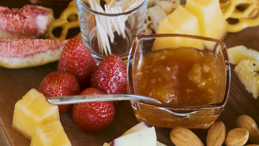 Assorted cheese platter with fresh figs, strawberries, nuts, pretzels and fruit jam on rustic wooden table. Cheese board. Appetizer and party food tasting