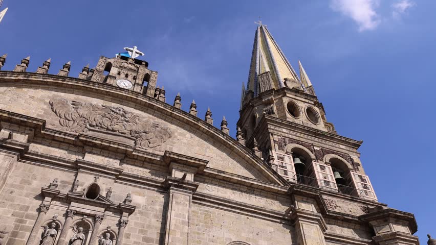 View of Guadalajara Cathedral with its iconic neo-Gothic spires and stone facade under a clear blue sky in Guadalajara, Jalisco, Mexico.