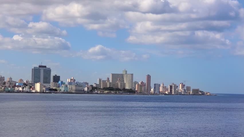 View of the Havana skyline along the coast with historic buildings and modern high-rises under a blue sky with scattered clouds in Havana, Havana, Cuba.
