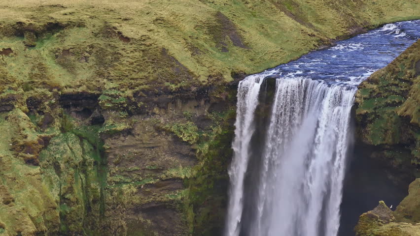 Touristic Skogafoss falls plunging over cliff face in Iceland. Telephoto aerial
