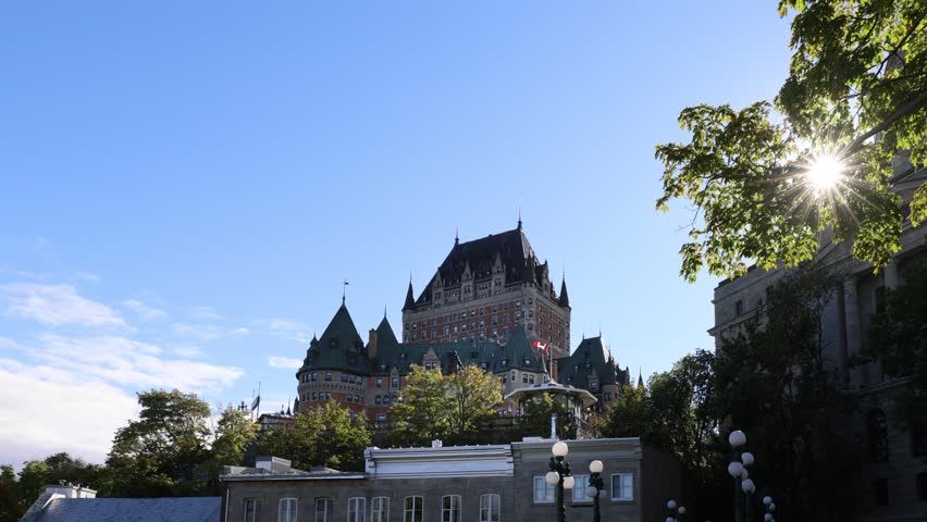 View of the historic Fairmont Le Chateau Frontenac hotel with its iconic towers and copper roofs under a bright blue sky in Quebec City, Quebec, Canada.