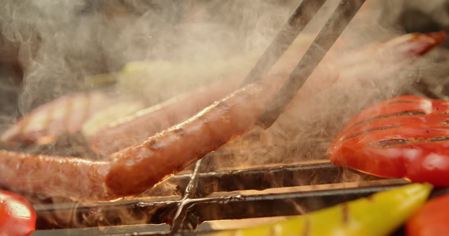 Tasty meat sausages grilling over open fire flames barbecue grill.