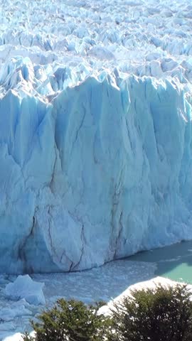 Witness the awe-inspiring beauty of the Perito Moreno Glacier. Immense ice walls meet the turquoise waters in Patagonia, Argentina, on a bright sunny day.