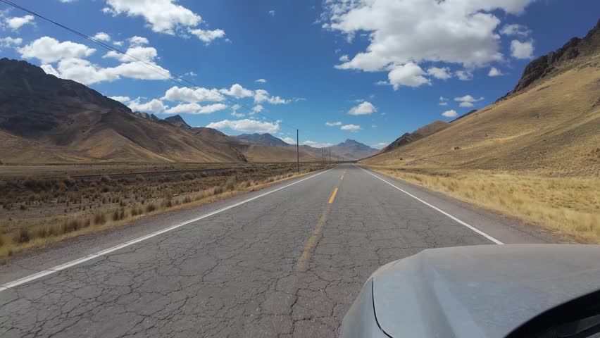 Driving Along Remote Mountain Highway Through The Peruvian Andes Under Blue Sky