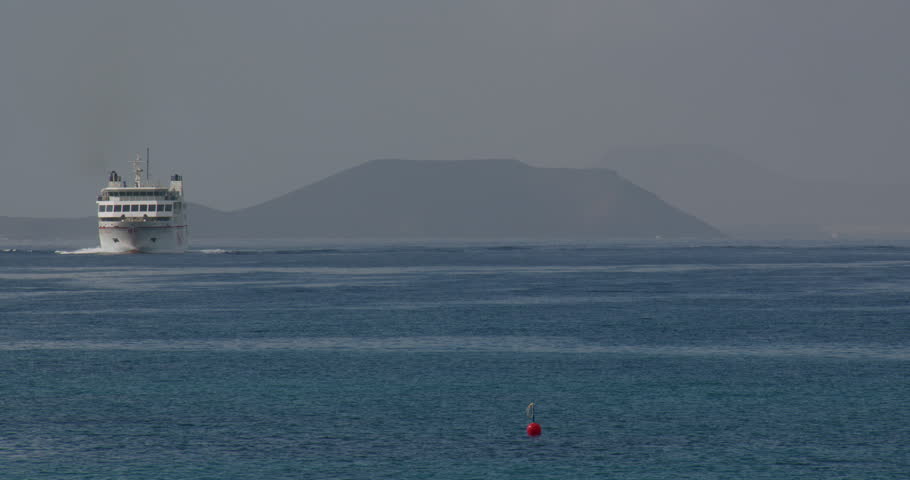 Wide shot looking out to see from Playa Blanca with ferry. Fuerteventura in background.